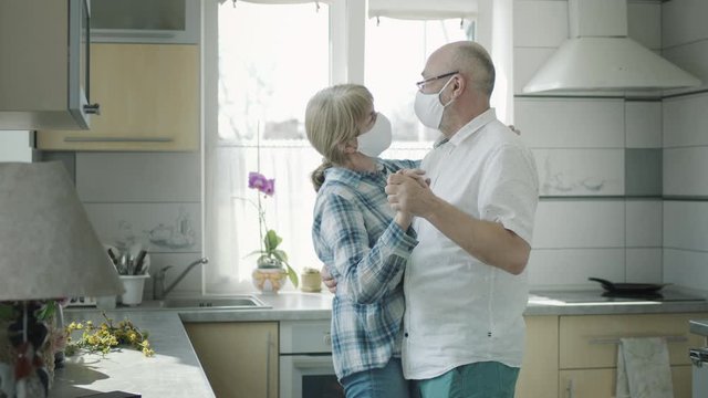 Man And Woman In Medical Masks Dancing In The Kitchen.