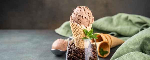 Delicious coffee or chocolate ice cream in waffle cone for dessert. Summer healthy food concept, lactose free. Copy space. Banner