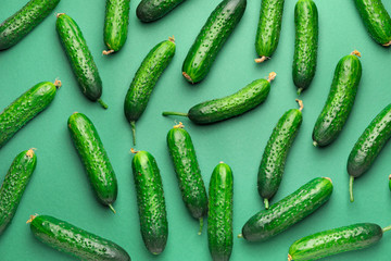 Many green cucumbers on color background