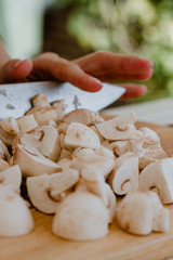 Fototapeta na wymiar Hands cutting mushrooms with a knife on a wooden board