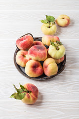 Naklejka na ściany i meble Fresh peaches fruits with leaves on light wooden background, top view