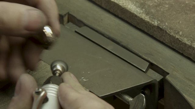 Jeweler cleans a diamonds ring with a polishing wheel brush