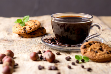 Black coffee in a glass cup with coffee beans. near cookies and hazelnuts