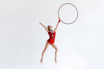 Full length portrait of gymnast in leotard suit making exercises with hoop, white background