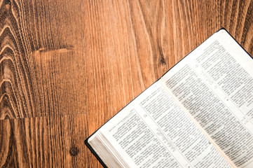 open book on a wooden background. holy bible on the table. notepad pages on the floor