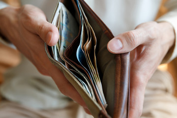 Wallet with money in the hands of a man on a light background
