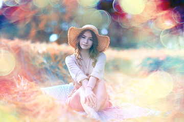 girl sitting in a field with a straw hat / summer vacation, rest young adult happy woman