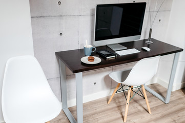 A minimal desk with a computer a couple of coffee and biscuits. Modern workspace