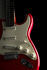 Fototapeta na wymiar A vibrant red electric guitar over a black background.