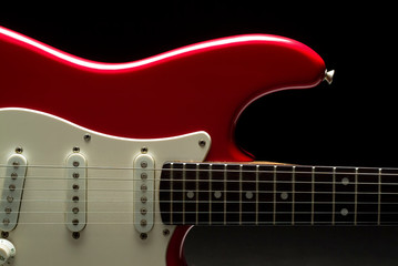 Obraz na płótnie Canvas A vibrant red electric guitar over a black background.