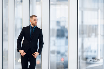 Portrait of handsome man standing in a suit and tie in front of glass door