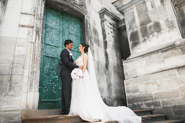 Gorgeous happy couple standing close to each other and looking in eyes at old city background, wedding photo, European city, wedding day in Lviv