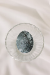 
marble blue easter egg in a glass goblet on a white background