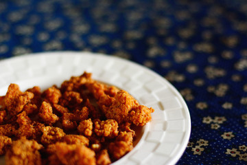 Crispy fried chicken skin on white dish, Thai snack.