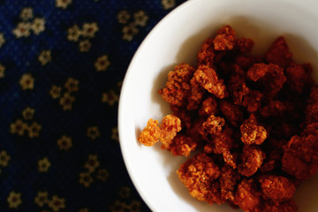 Crispy fried chicken skin on white dish, Thai snack.