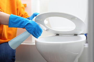 Cleaning the toilet. A woman cleans the toilet with a disinfectant, disinfects the toilet seat and toilet bowl.