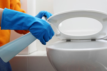 Disinfection of the toilet bowl, cleaning the toilet. A woman cleans the toilet with a disinfectant, disinfects the toilet seat and toilet bowl.