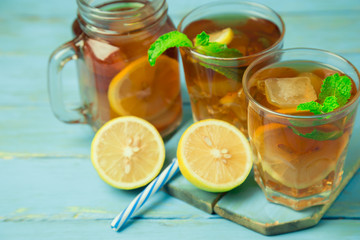 Iced tea with lemon slices and mint on wood background