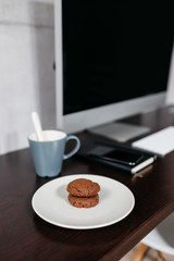A minimal desk with a computer a couple of coffee and biscuits. Modern workspace