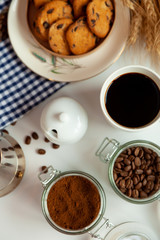 White cup of coffee and homemade round cookies with chocolate chips. Breakfast is on the table. Food at home. Still life. Coffee and coffee beans. An invigorating drink. Top view, flat lay.