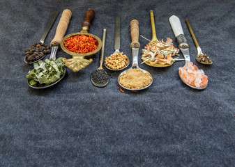 Fototapeta na wymiar Various teas and dried herbs assortment on spoons in rustic style on balck background.