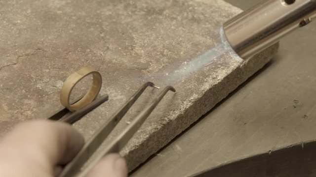 jeweler soldering pieces of gold on golden ring, tool preparation