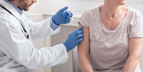 Senior woman getting vaccination injection from doctor