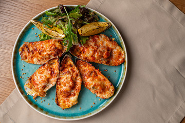 delicious cooked mussels with sauce, lemon and garlic bread and butter on a black plate on the dark wooden background, side view, horizontal