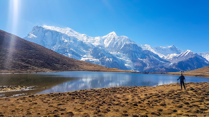 Trekking Young Man at the Ice Lake, the view on Annapurna Chain, Annapurna Circuit Trek, Nepal....