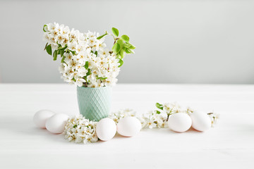 White Easter eggs and spring branch with flowers on wooden background. Spring easter greeting card.Flowers Cherry flowering.Spring flowers. Beautiful Orchard.Springtime