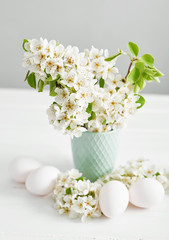White Easter eggs and spring branch with flowers on wooden background. Spring easter greeting card.Flowers Cherry flowering.Spring flowers. Beautiful Orchard.Springtime