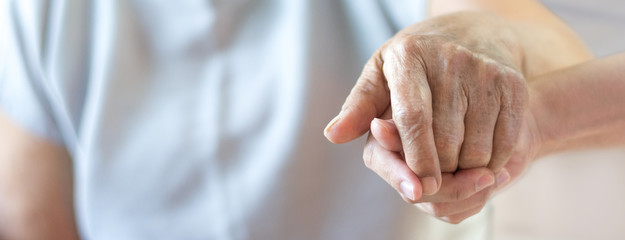 Caregiver, carer hand holding elder hand in hospice care background. Philanthropy kindness to...