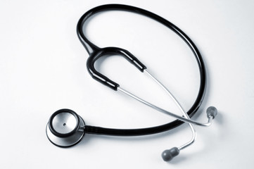 A single black stethoscope over a white tabletop surface. 