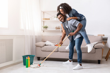 Playful African American Couple Fooling Together During Tidying Flat
