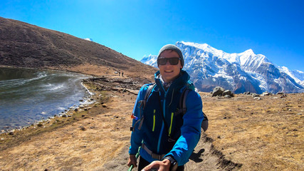 A man trekking along the Ice Lake, Annapurna Circuit Trek detour, Himalayas, Nepal, surrounded by...