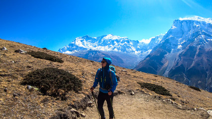 Fototapeta premium A man trekking on the Annapurna Circuit Trek, Himalayas, Nepal. Panoramic view on snow caped Annapurna chain. Lots of dried grass. High altitude, massive mountains. Freedom and adventure