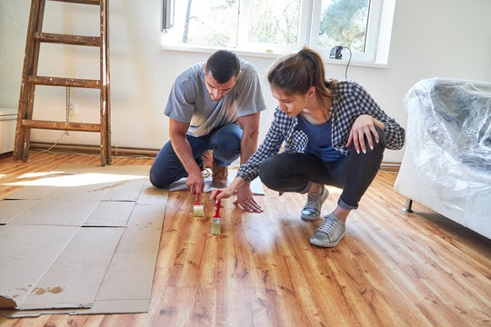 Young couple at the parquet paint as a home improvement