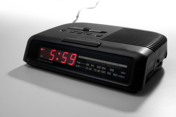 A radio alarm clock with an early hour on it's display over a white background.