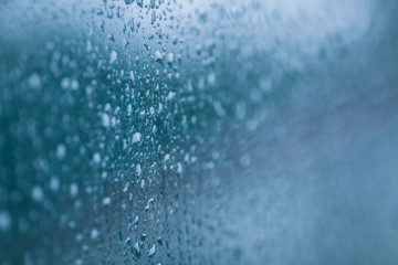 Drops on the glass. Abstract blurred background with wet surface, raindrops on the window.