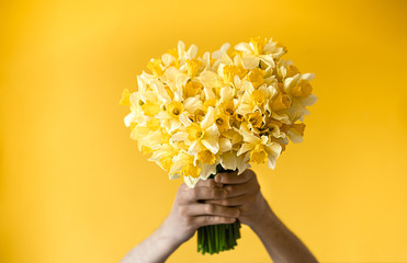Background male hands with a bouquet of flowers .