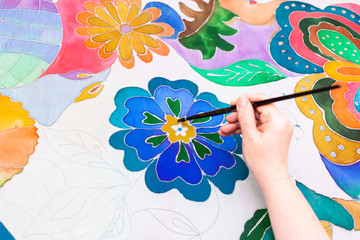 craftsman paints flower in batik on silk canvas