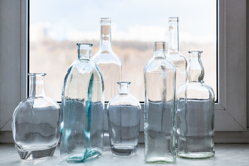 many clear bottles on windowsill and view of park