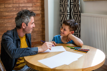 Happy dad and little kid son laughing drawing together 