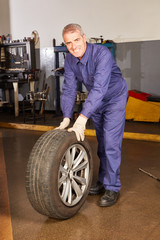 KFZ Mechaniker beim Reifenwechsel als Service