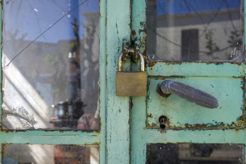 Old rusty padlock on shabby glass door to empty house as symbol of crysis and bankruptcy. 