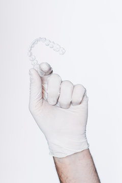 Hand in protective glove holding dental aligner