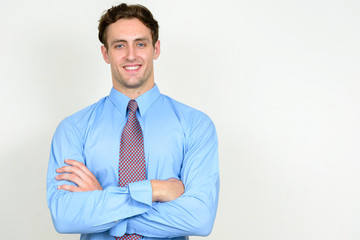Portrait of happy young handsome businessman smiling with arms crossed