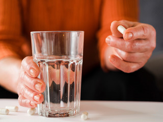 Close-up patient holding pill and glass of water
