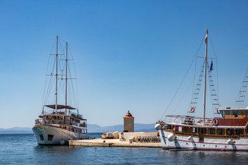 Fototapeta na wymiar Port and pier of village Postira on island Brac in Croatia with tourist and fishing boats and lighthouse