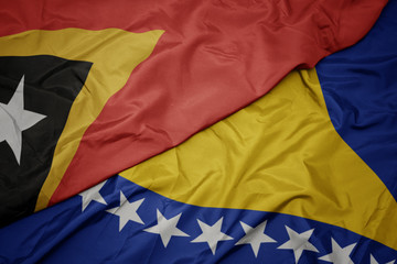 waving colorful flag of bosnia and herzegovina and national flag of east timor.